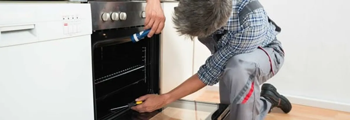 Oven repair technician inspecting and servicing an electric oven in Wichita, KS